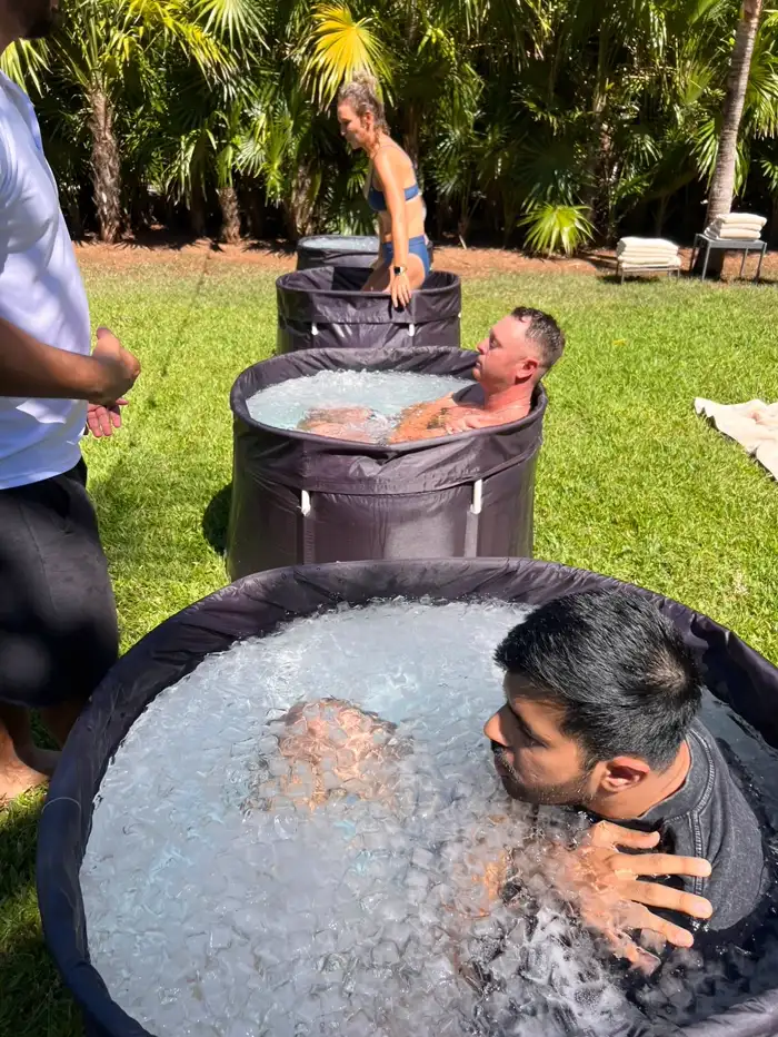 Un huésped dentro de la tina con el agua llena de hielo hasta el borde, y una mano en su hombro desde afuera