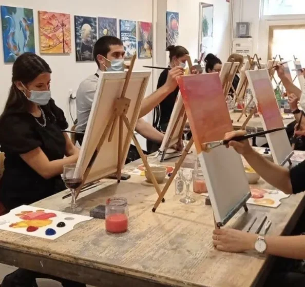 Participantes pintando lienzos en caballetes durante un taller de Splat Paint